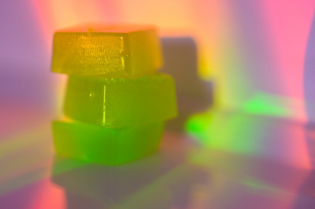 How long do edibles last: A photo of green hard candies with a pink light on them.
