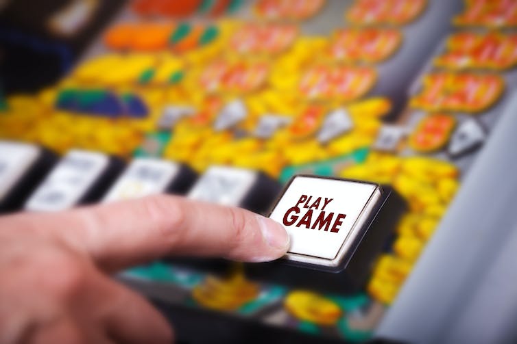 Finger pressing play button on slot machine